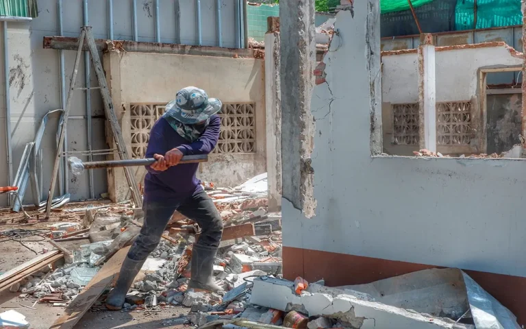 a man in a hat and boots holding a sledgehammer
