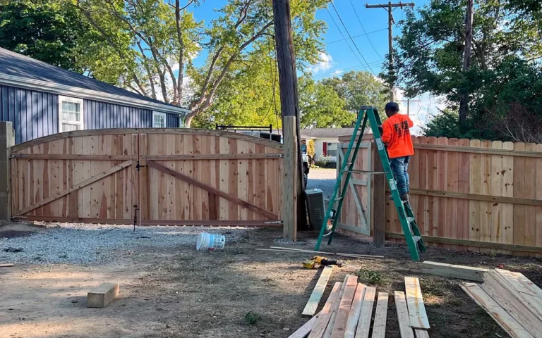a man standing on a ladder next to a fence