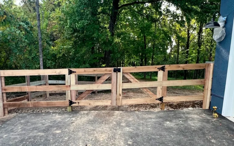 a wooden gate with a fence and trees in the background